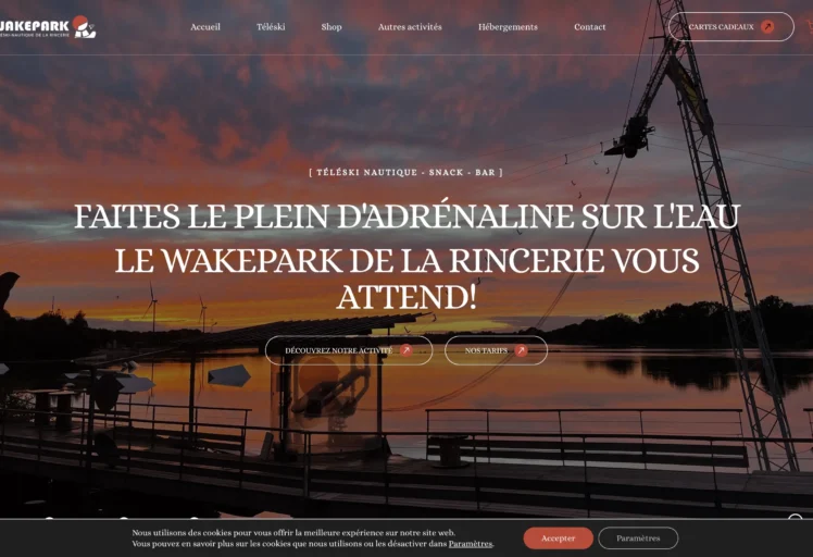 Capture d'écran du site du Wakepark de la Rincerie, proposant téléski nautique, bar et snack, avec un coucher de soleil sur le lac et une ambiance sportive.