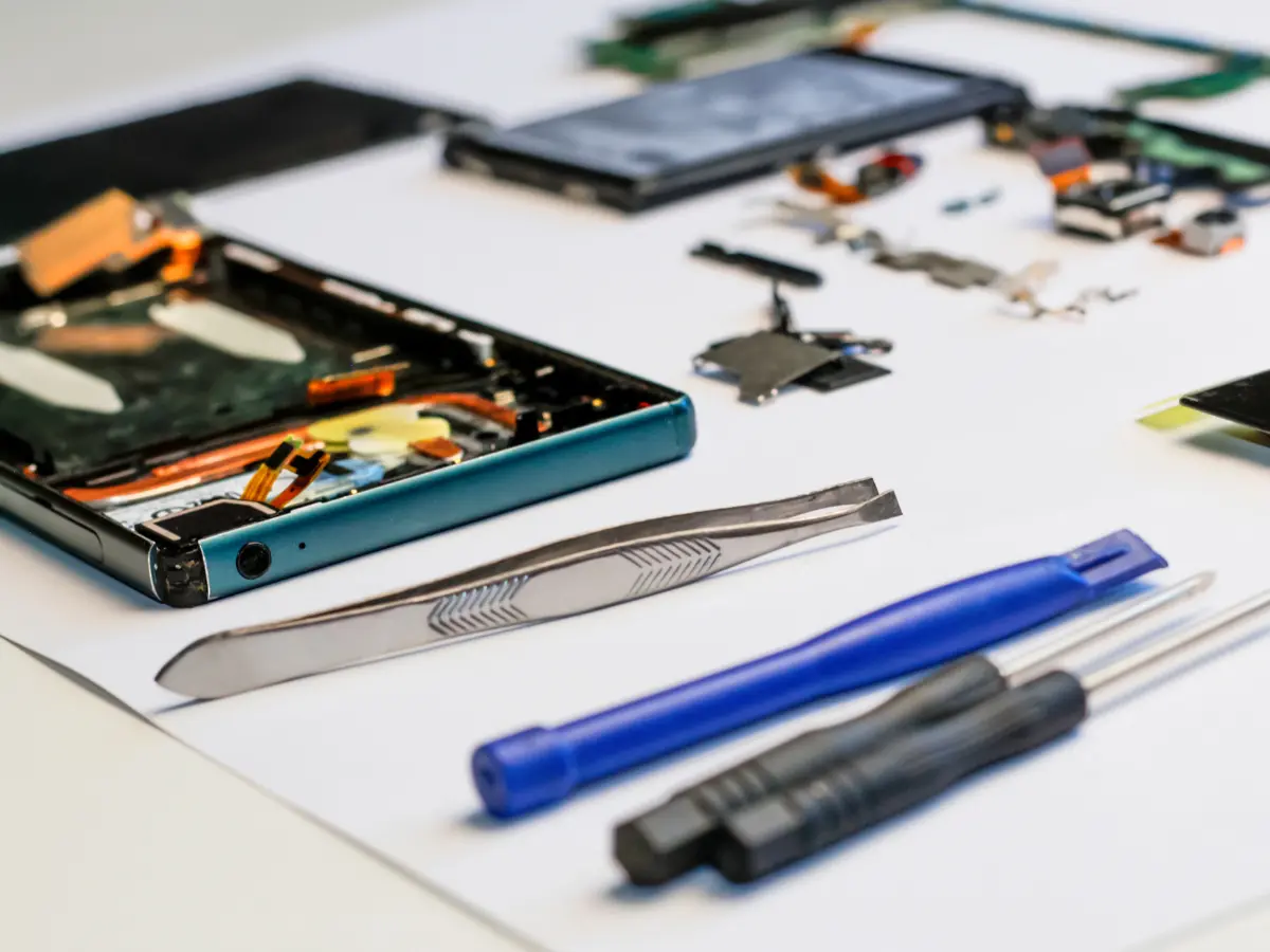 Téléphone démonté pour réparation, entourée des outils